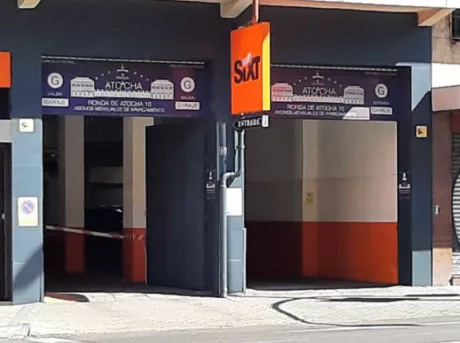 Entrada al Parking Estación de Atocha: el cartel de la empresa Sixt en naranja en el lateral del parking. La entrada está pintada de gris oscuro.