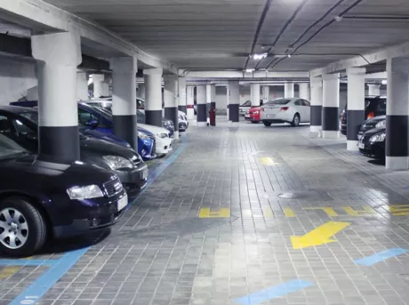 L'allée du parking Atocha avec les places de stationnement à droite et à gauche marquées par des bandes bleues.  